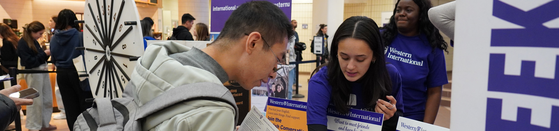 A Western volunteer assisting a student in finding programs at Western International