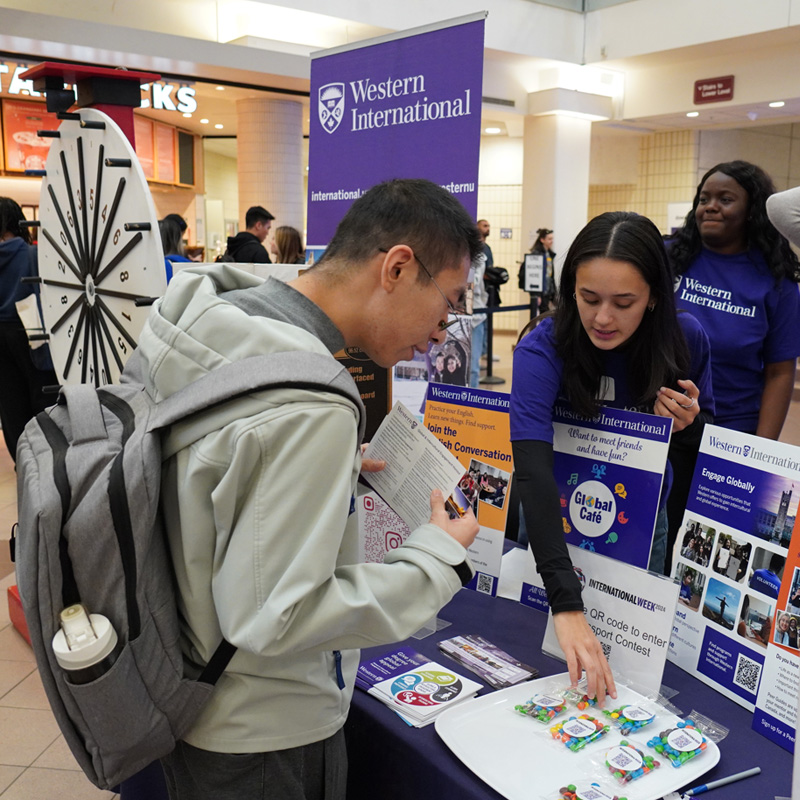 A Western volunteer assisting a student in finding programs at Western International